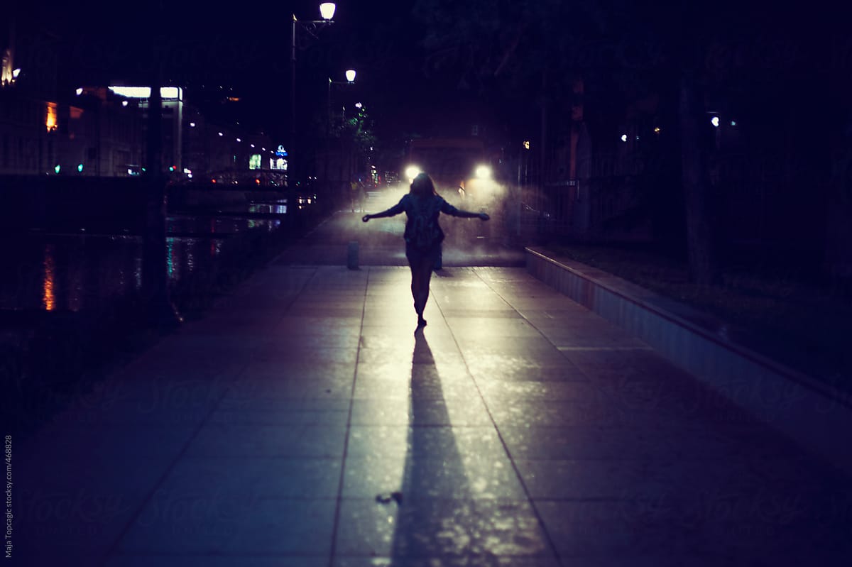 Young woman standing in the night in front of a vehicle lights