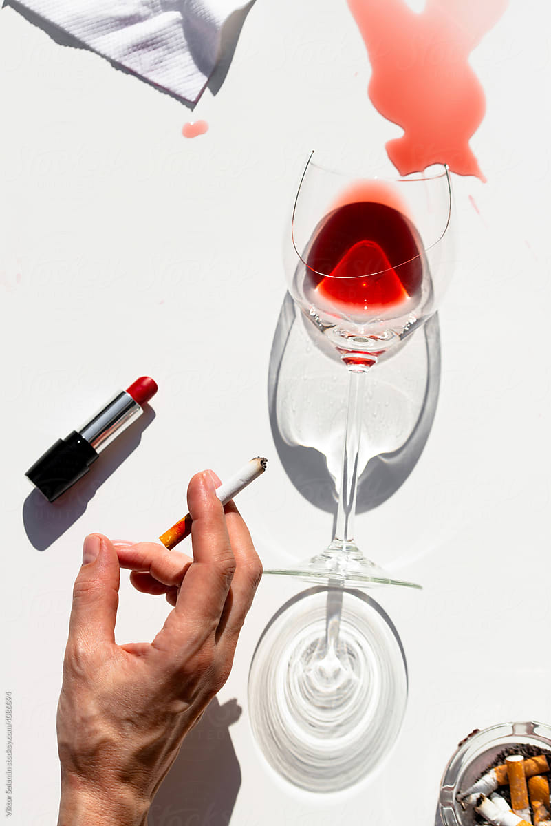 Person smoking at table with wineglass