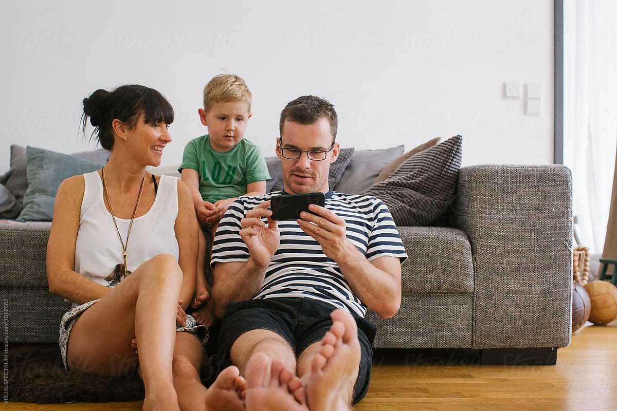 Family at Home - Young Parents With Small Boy Watching Video on Cellphone