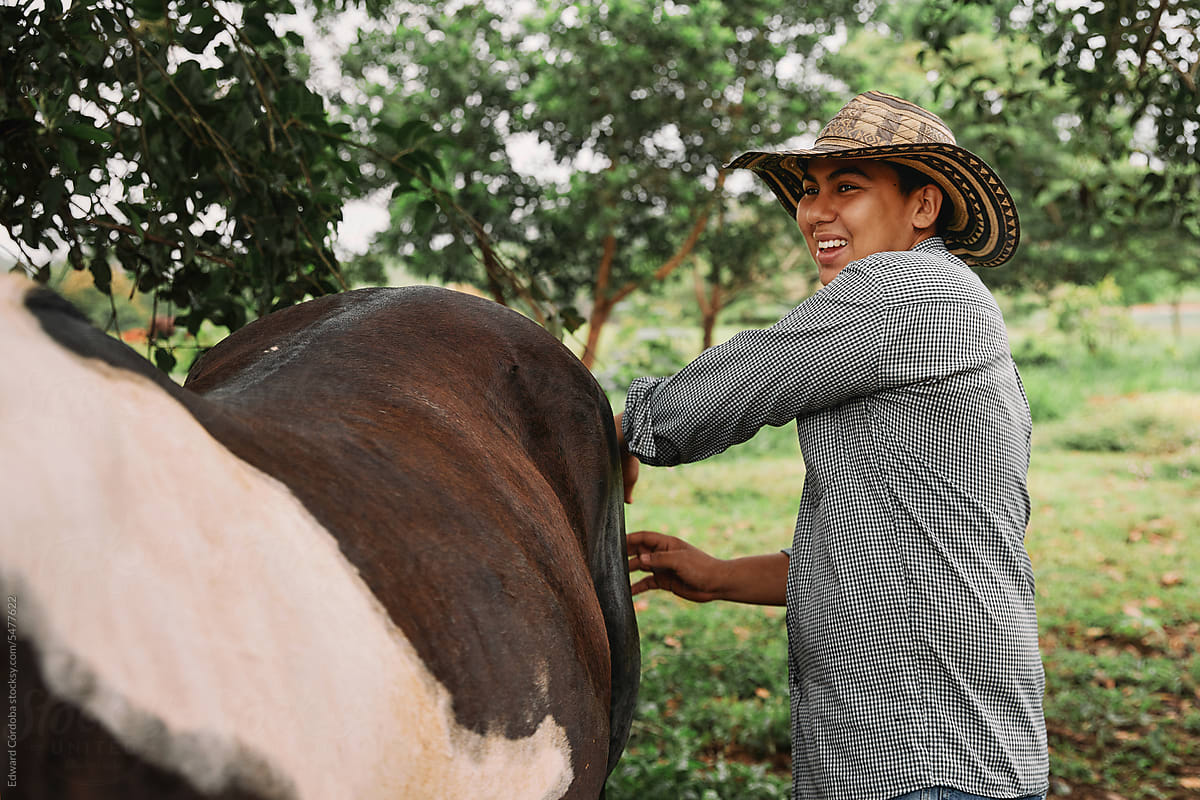 Smiling young man brushing his horse in a rural area of Colombia