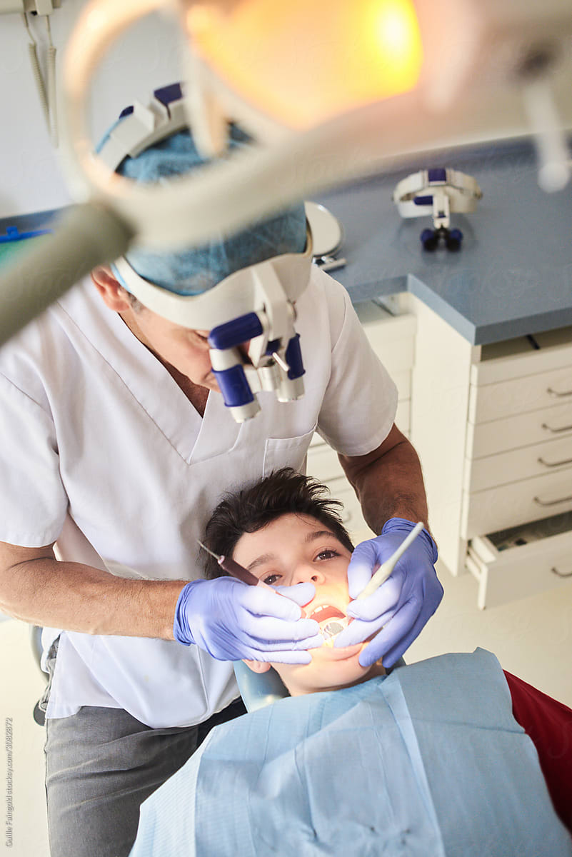 Dentist using mirror for checking teeth of patient