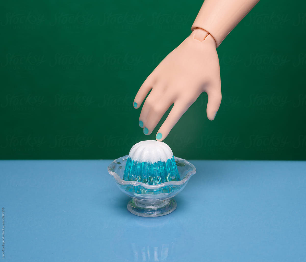 Miniature mountain-shaped jelly dessert being touched by a pointing finger