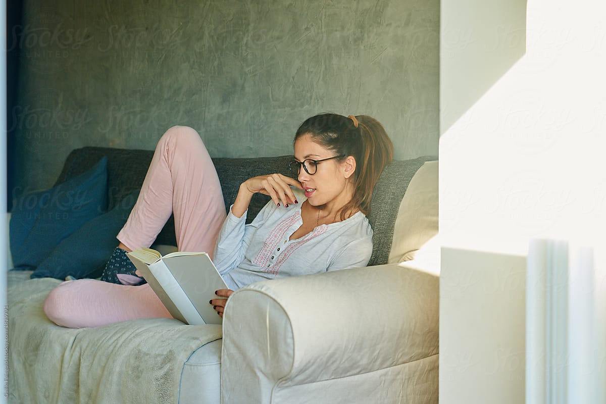 Woman relaxing with book on sofa