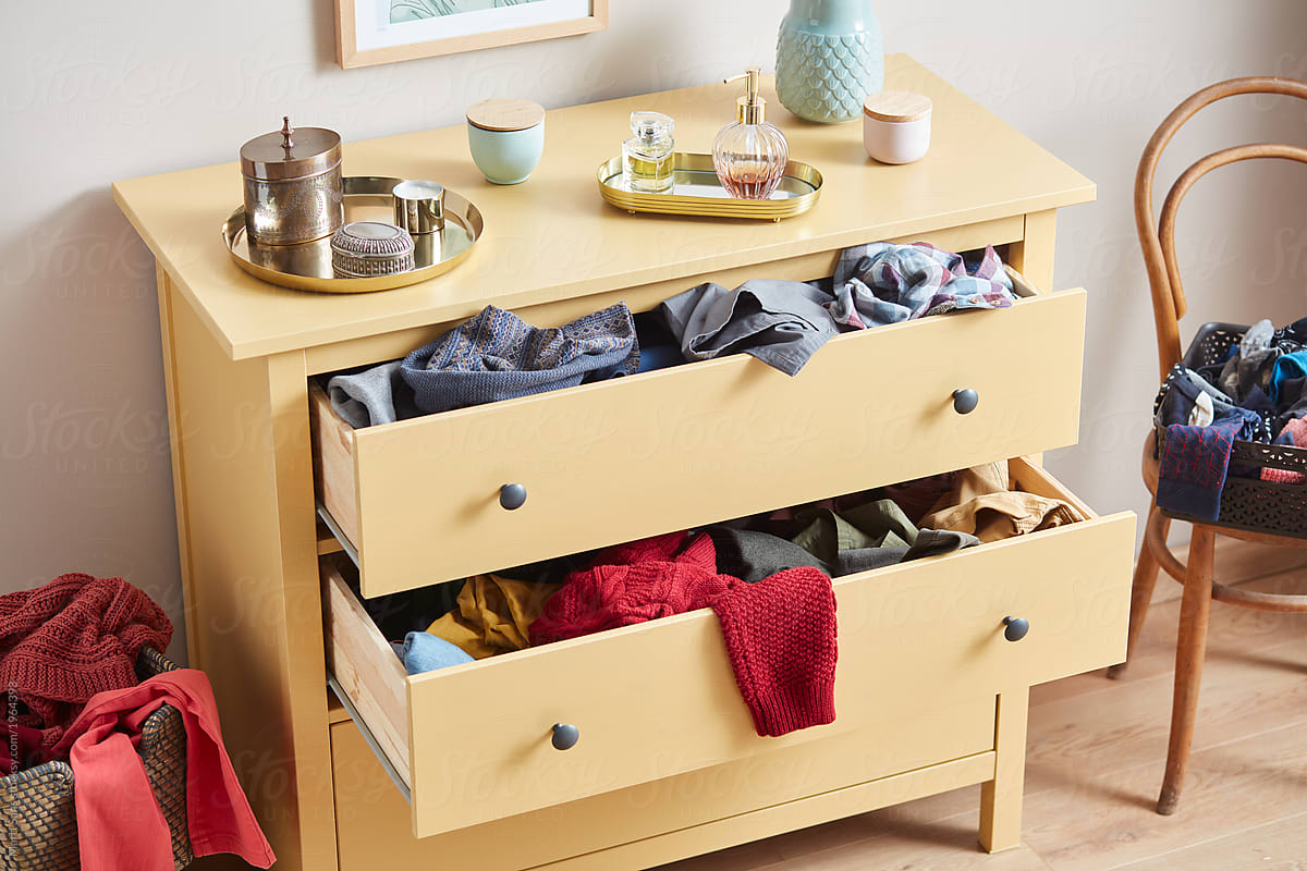 Dresser with messy clothes.