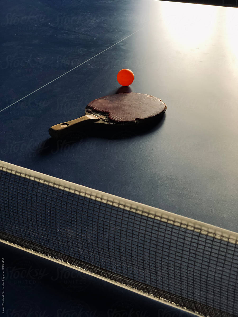 table tennis racket and an orange ball rested on the table tenni