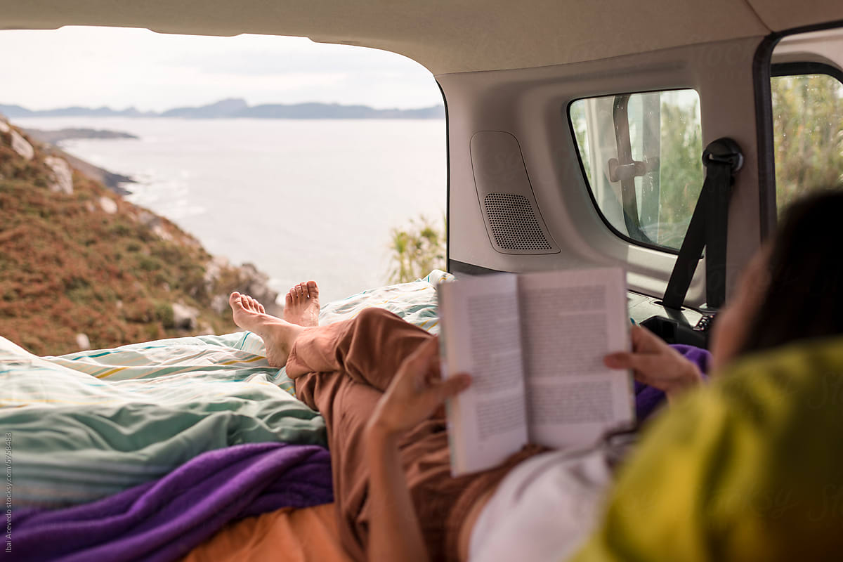 Relaxed woman reading on camper van bed