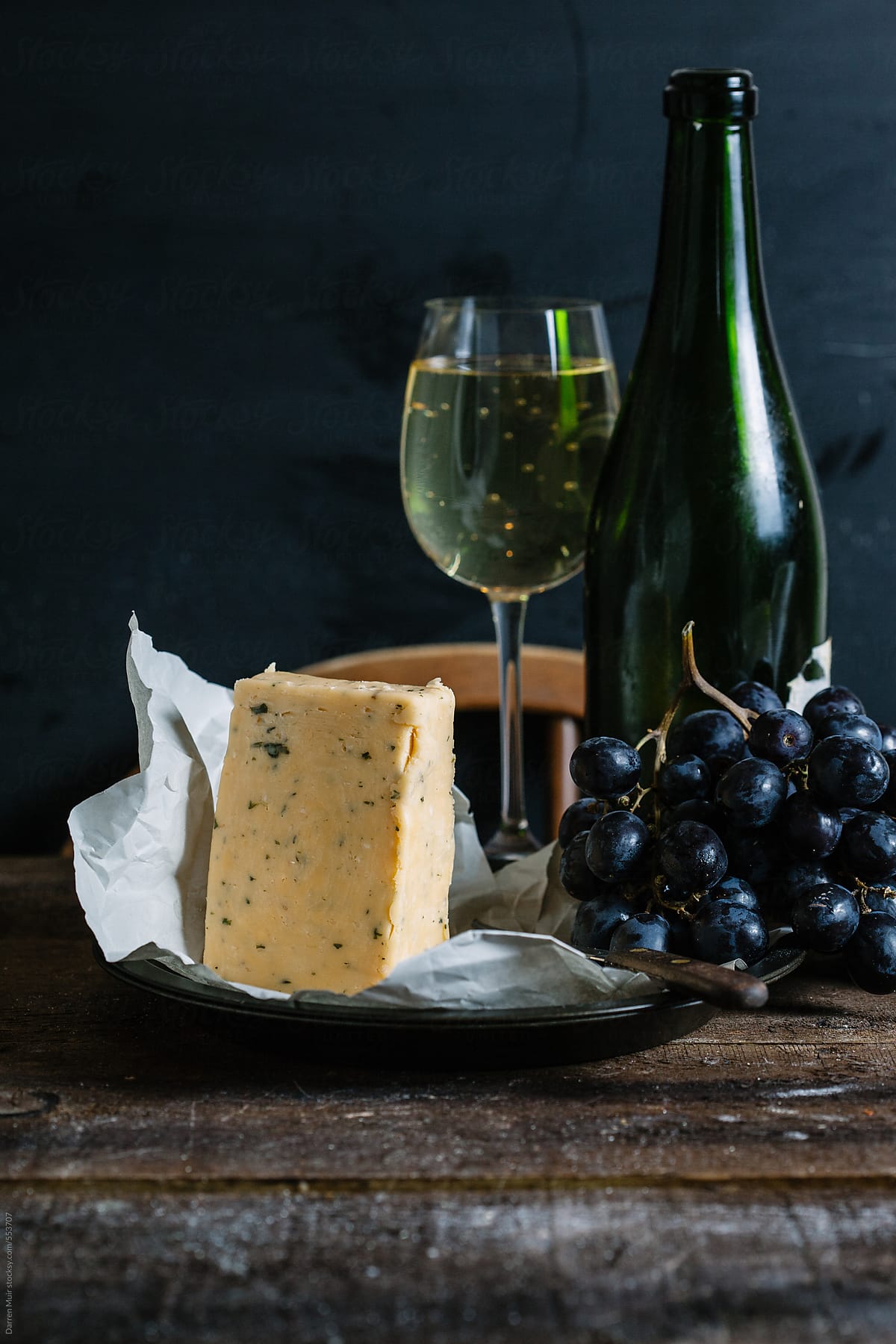 Cheese,grapes and wine on wooden table with dark background. Side view.
