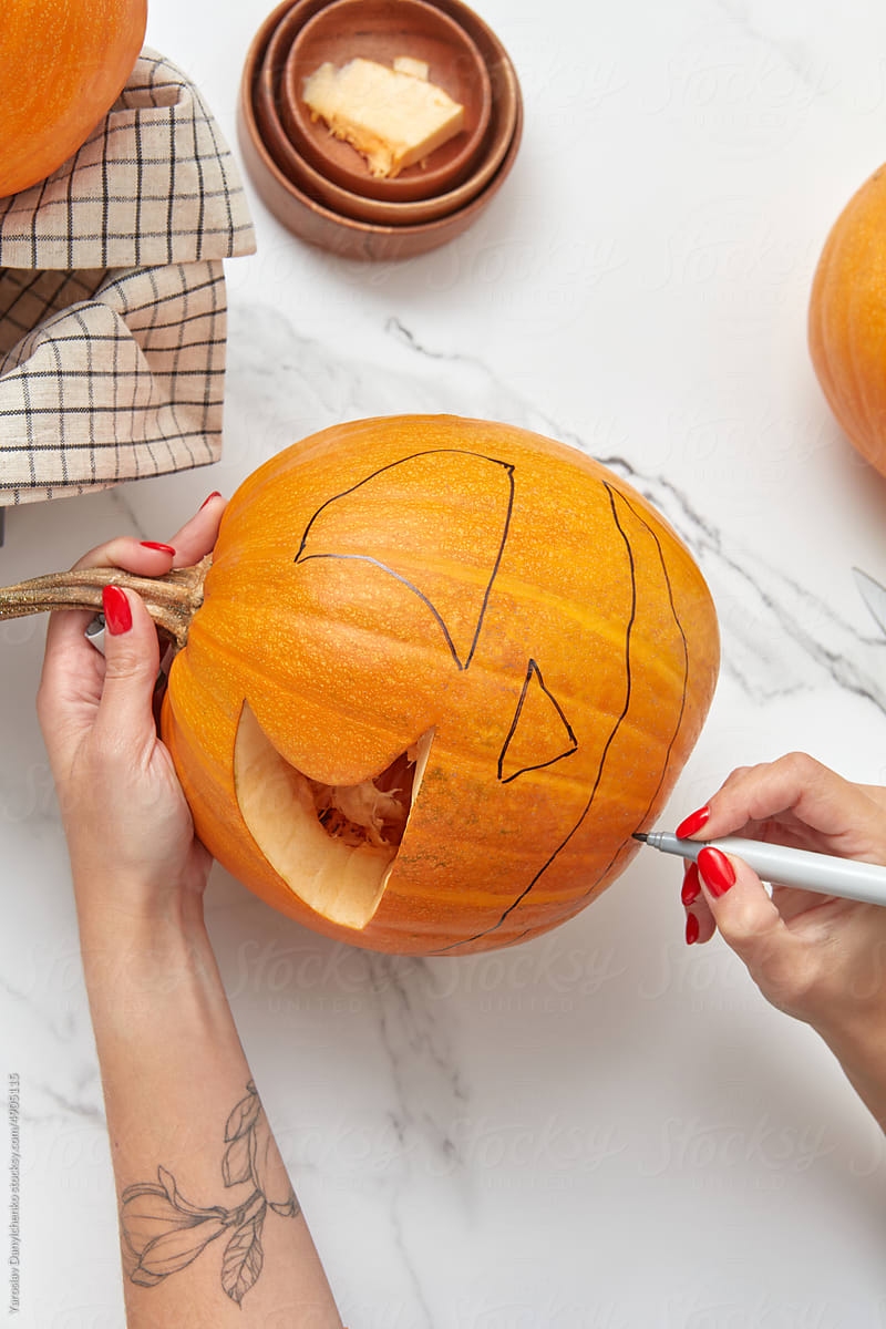 Halloween pumpkin being carved by female hands.