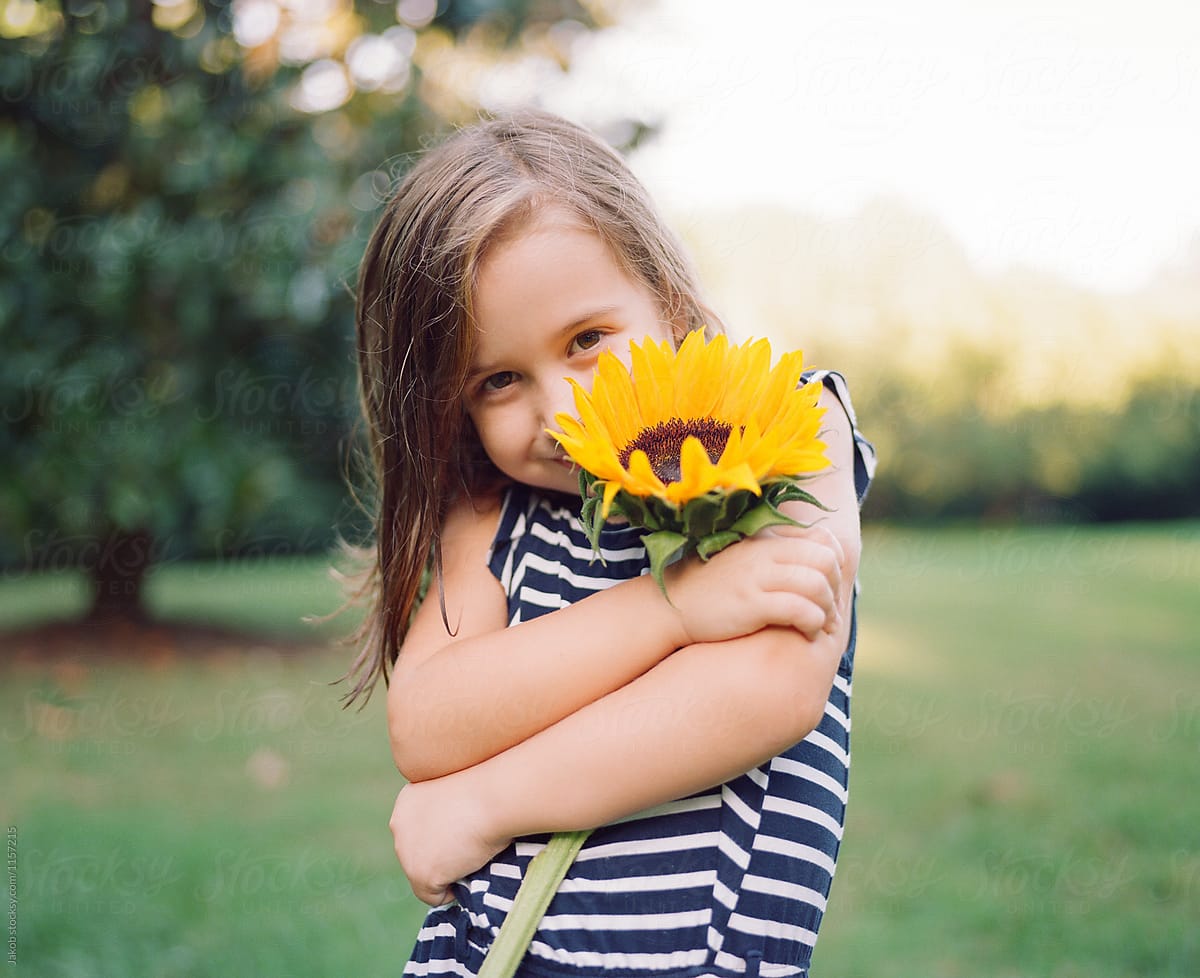 Cute Young Girl With A Big Sunflower Del Colaborador De Stocksy 
