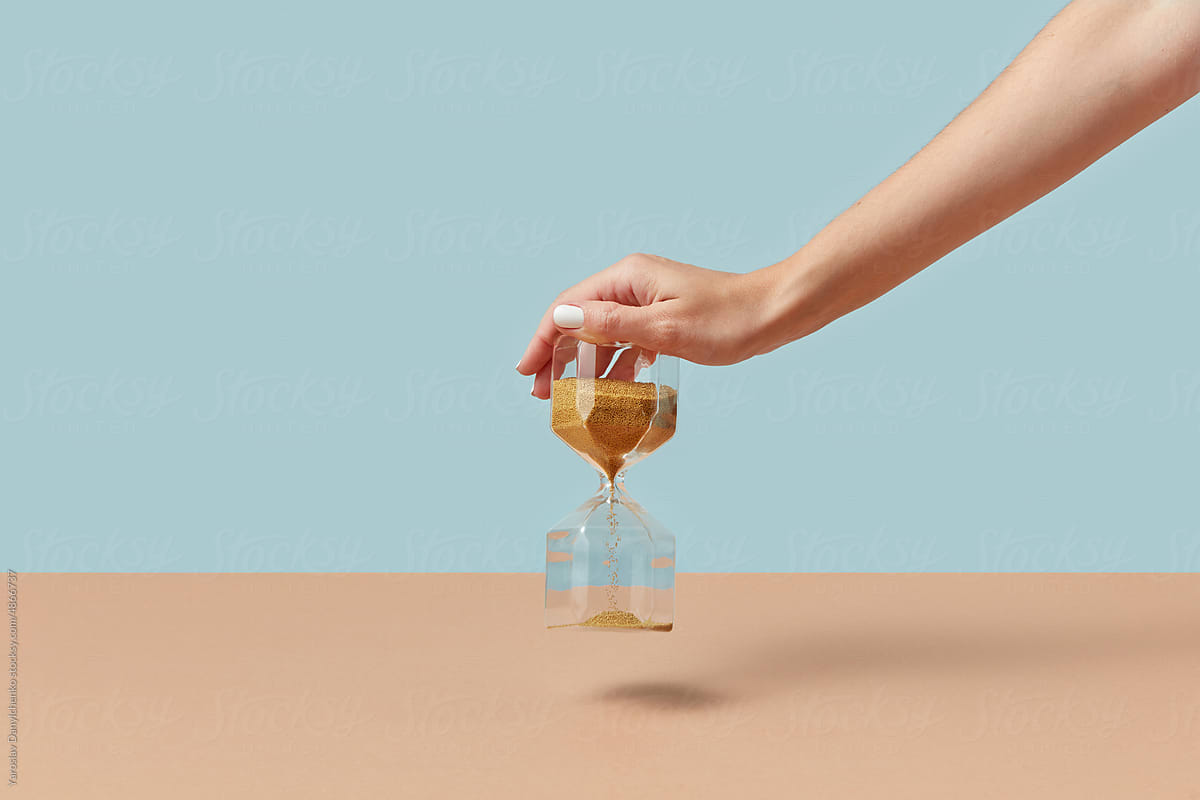 Sandglass with golden sand in female hand.
