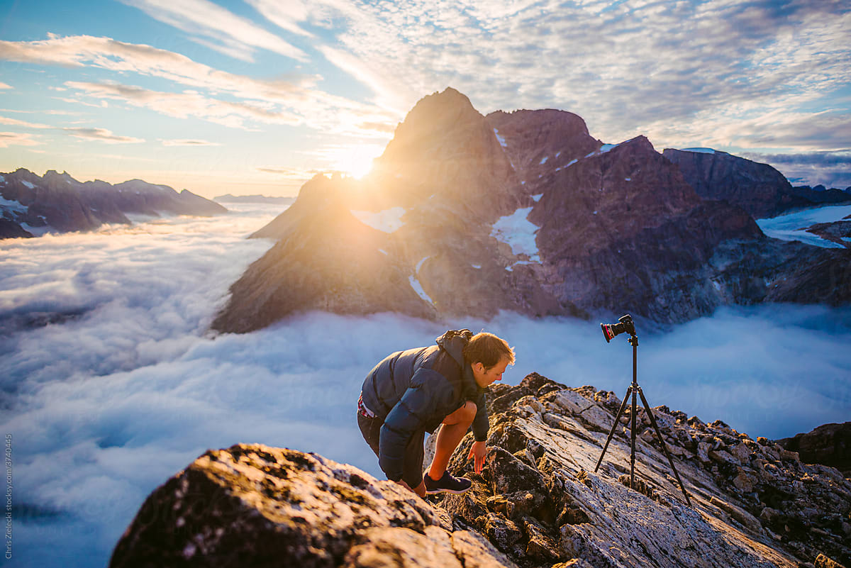 Male photographer climbing mountain near photo camera in morning