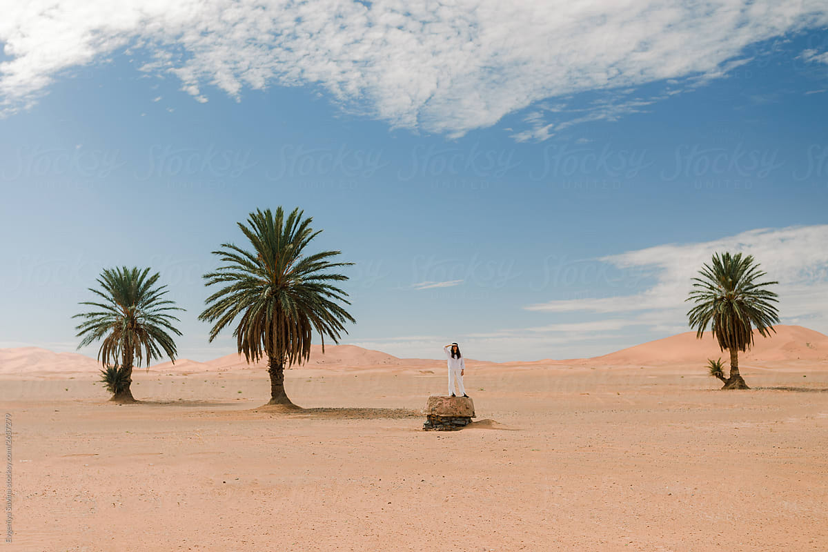 Green palms and a person in white clothes in the desert
