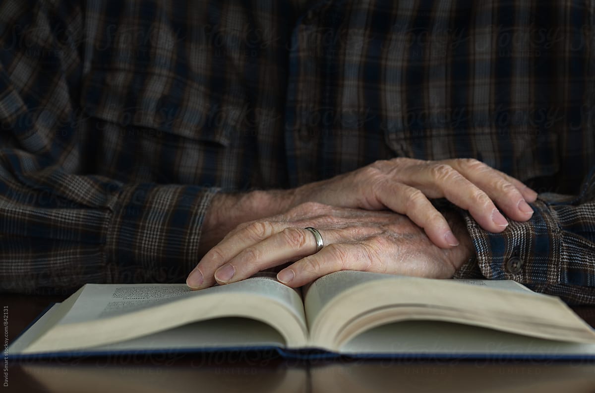 Hands of a senior man on the pages of an open book.