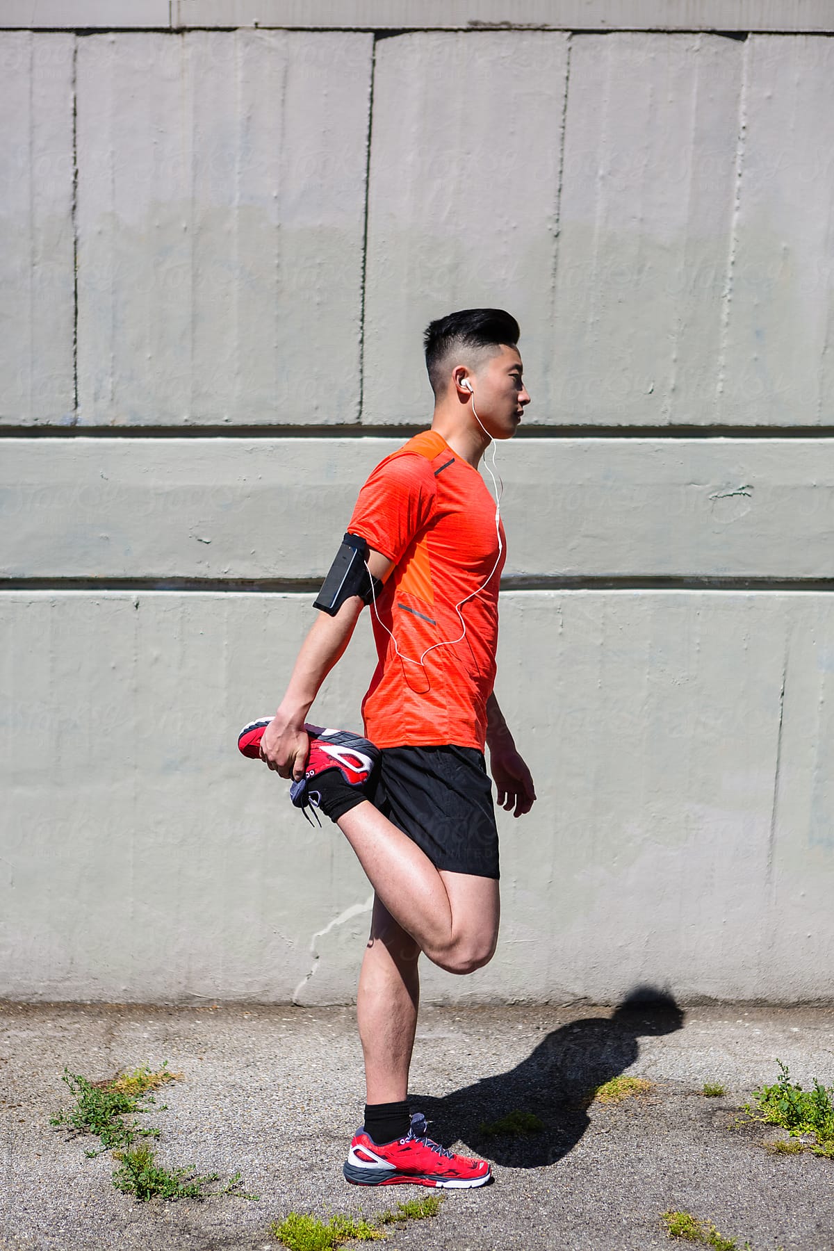 Young Chinese Man Stretching Legs Before Running