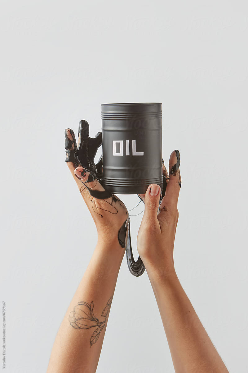Woman holding barrel with spilled black oil.