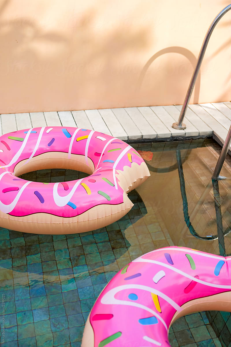 two bright inflatable donuts are swimming in the pool