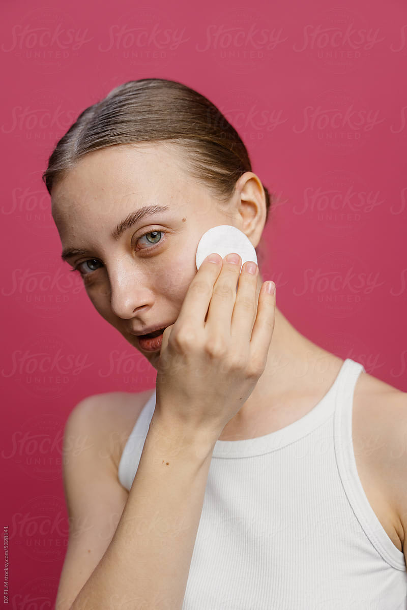 A woman wipes her face with a cotton pad