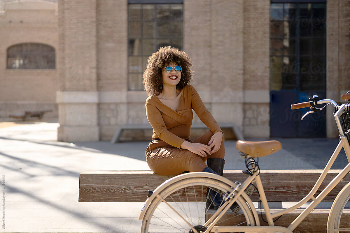 Smiling black woman sitting near bicycle