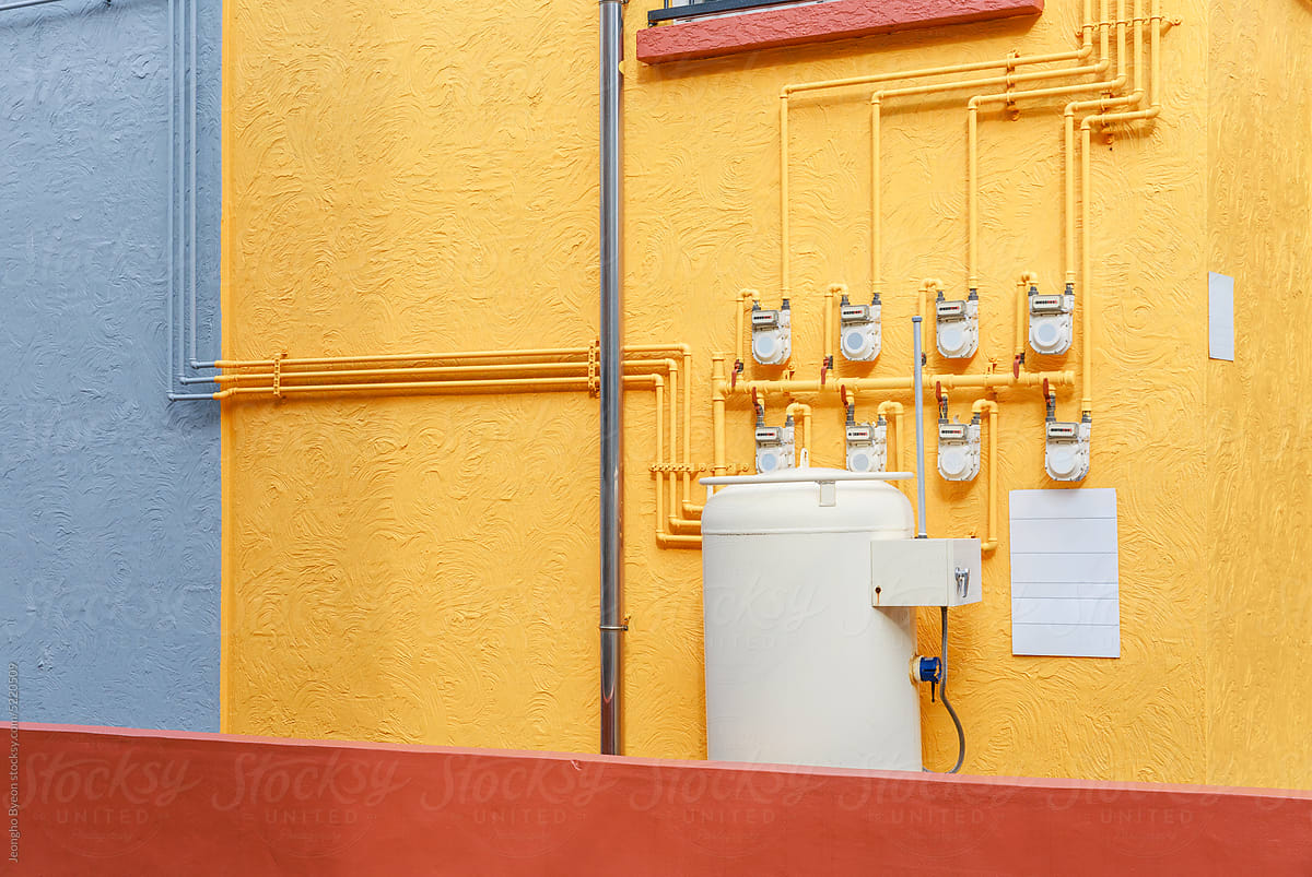 Gas installations installed on the wall of a yellow building.