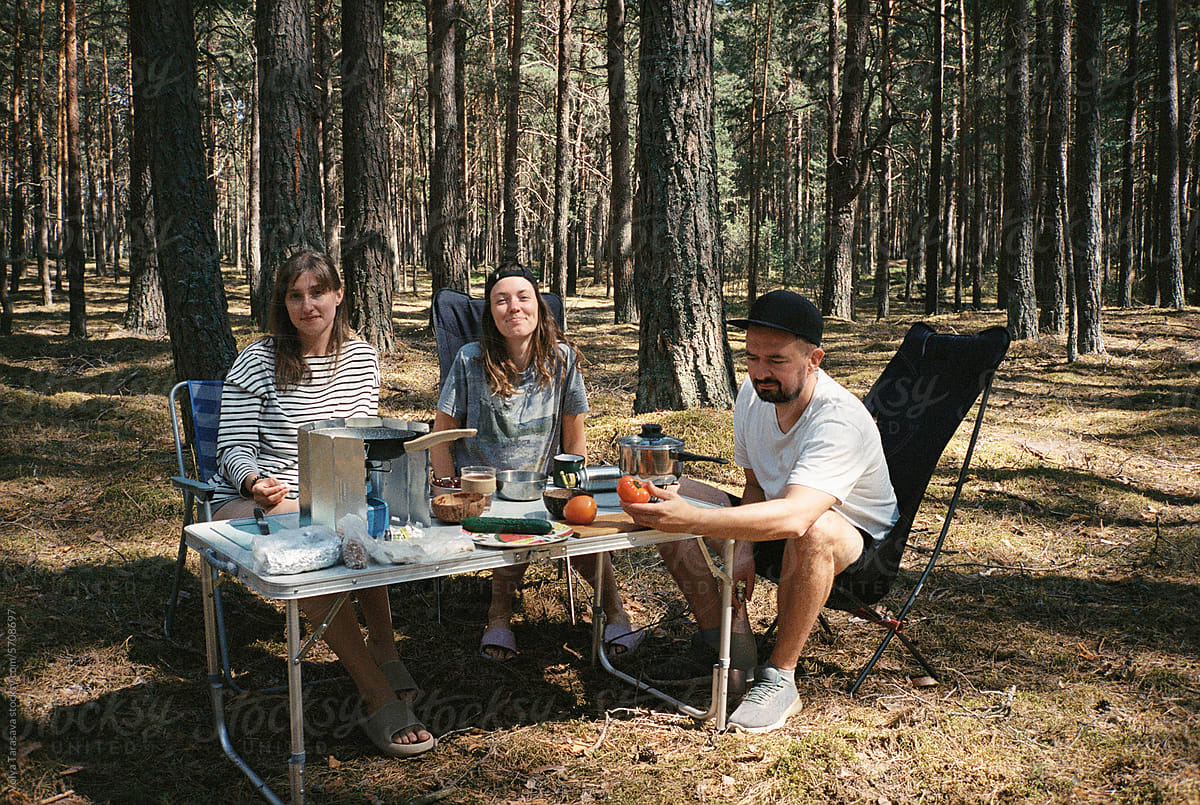 Three young friends at camp table in a forest