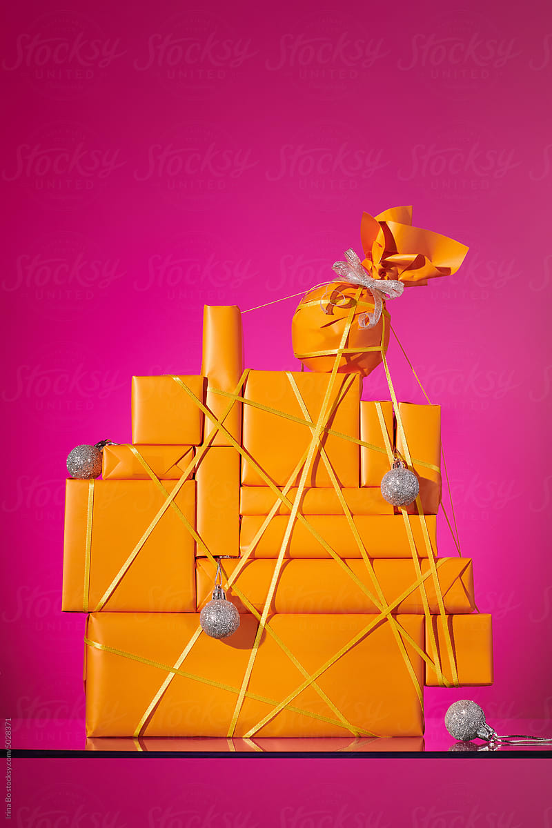 Stack of gifts with christmas balls on a pink background. Still life