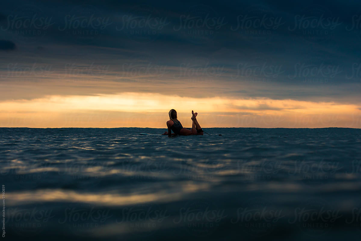 Silhouette Of Woman In The Ocean Lying On Surfboard At Sunset Beautiful Clouds Vivid Colors