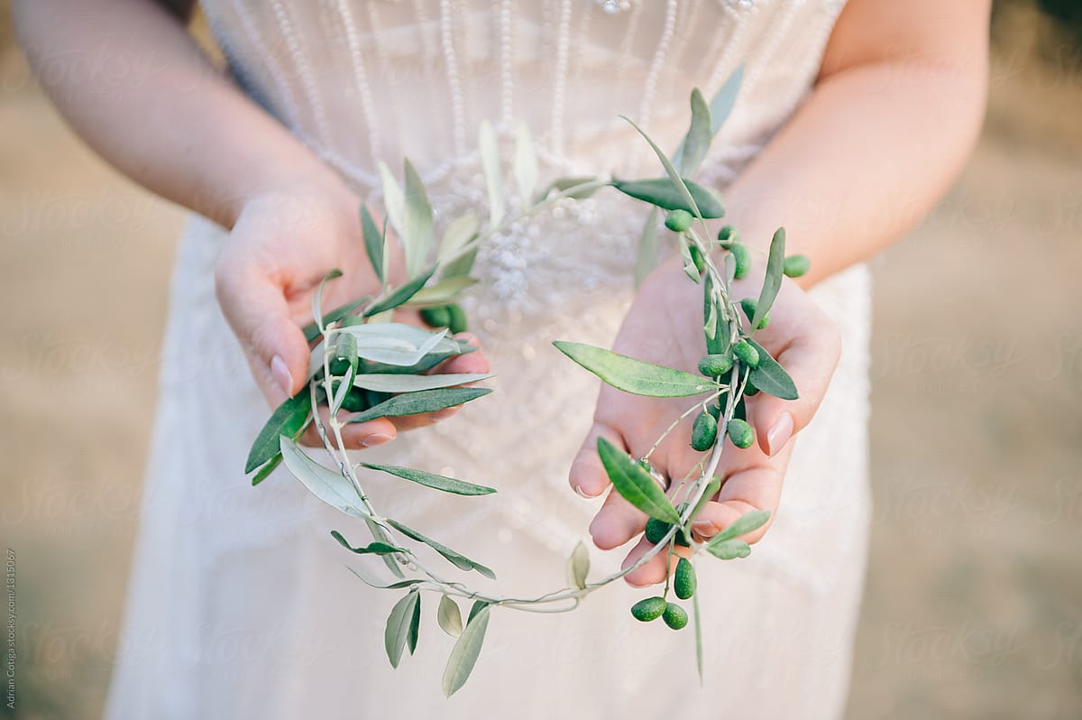 Hands holding wreath made by olive branches