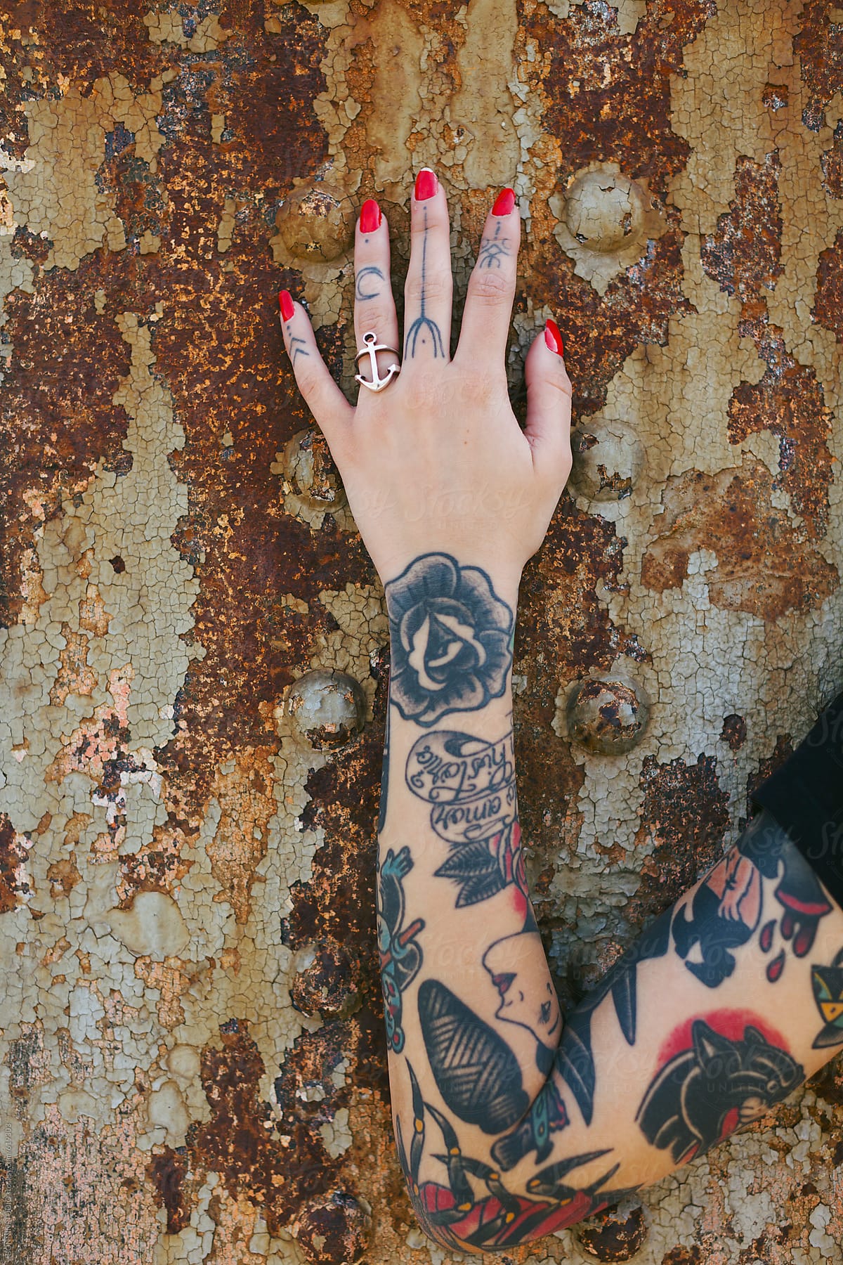 Alternative woman\'s tattooed arm in front a rusted wall.