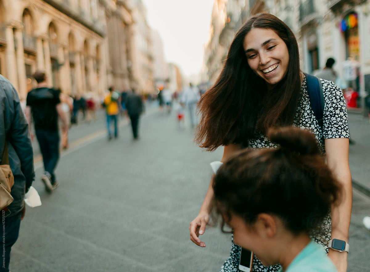 Woman and kid playing in crowded old italian city street smiling