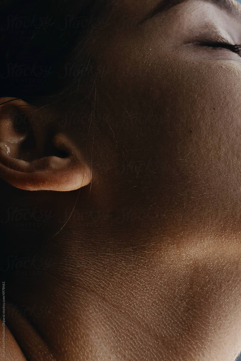 Half face profile portrait of a tanned woman with closed eyes