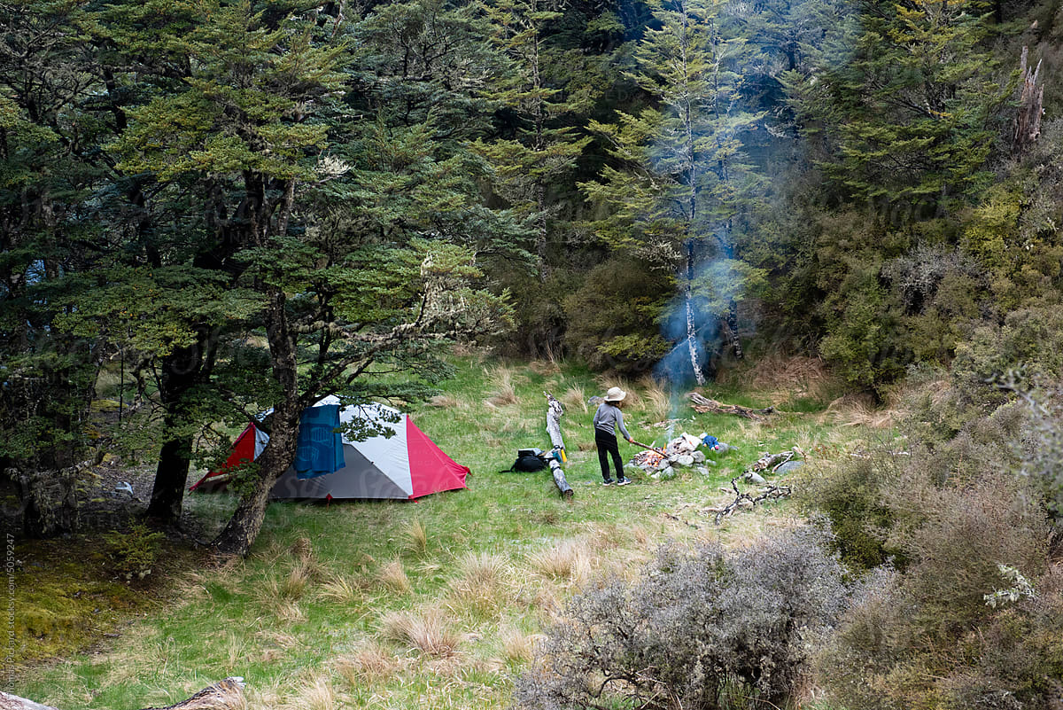 Girl tending camp fire, New Zealand.