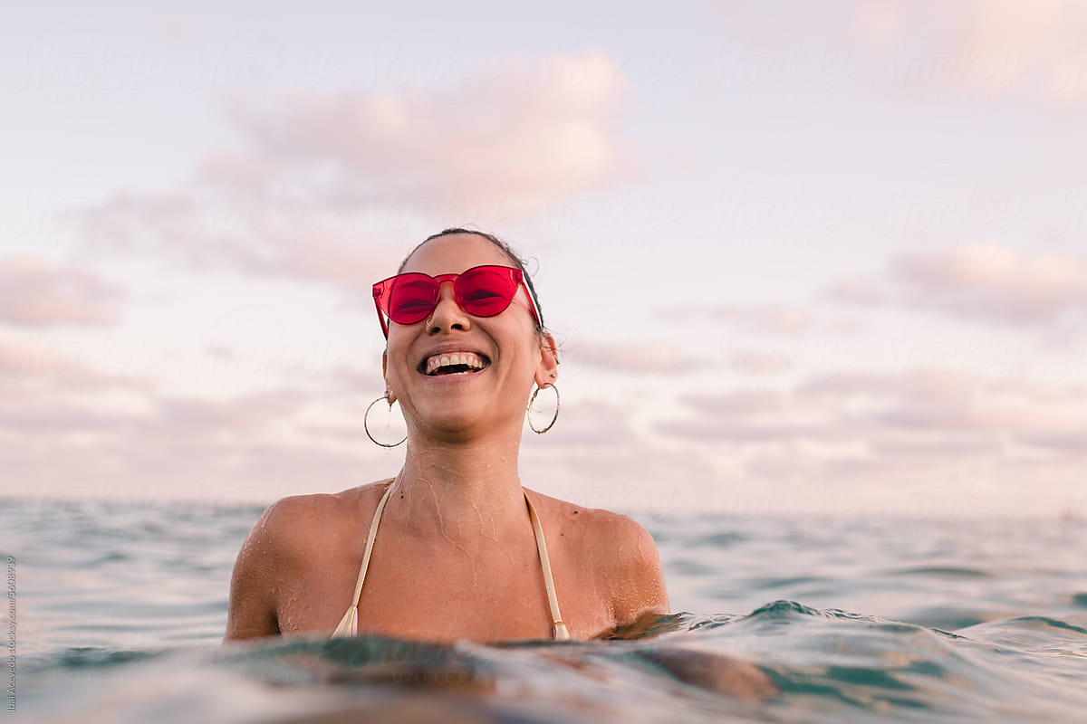 Happy stylish woman enjoying sunset sea bathing
