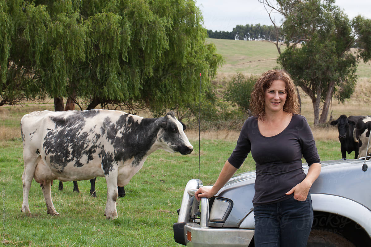 Female Dairy farmer standing in paddock against farm truck