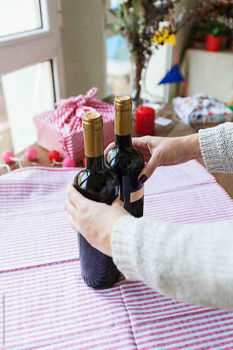 Hands wrapping wine bottles with fabric