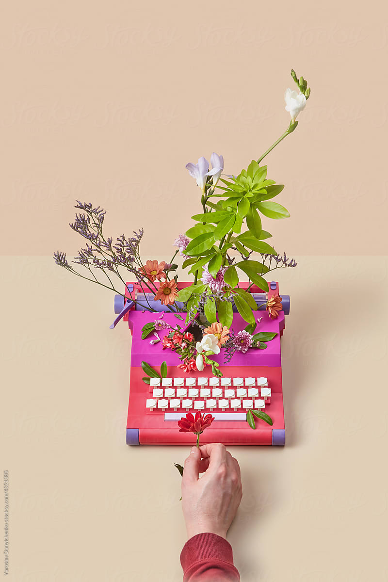 Man\'s hand holding flower near retro styled typewriter