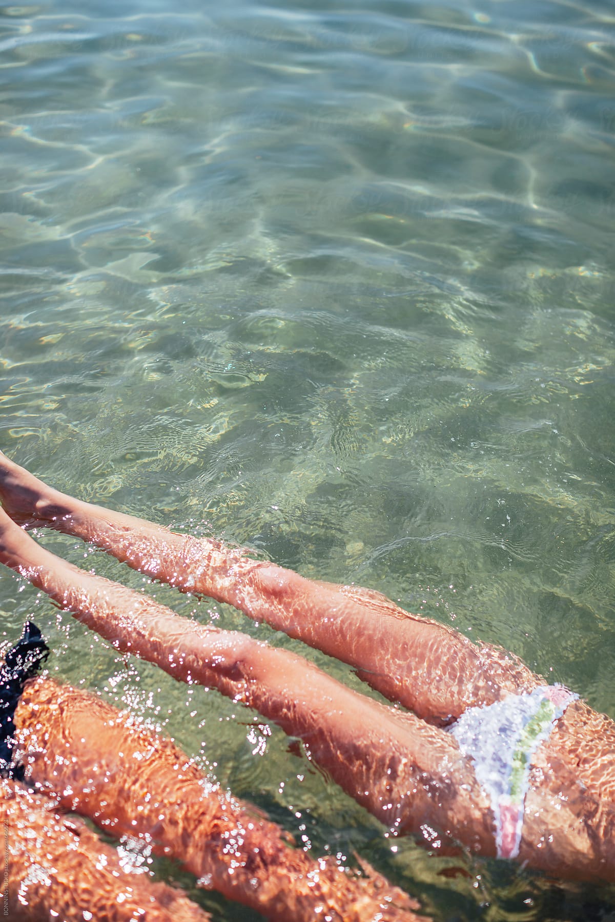 Young women legs bathing in a clear blue sea.