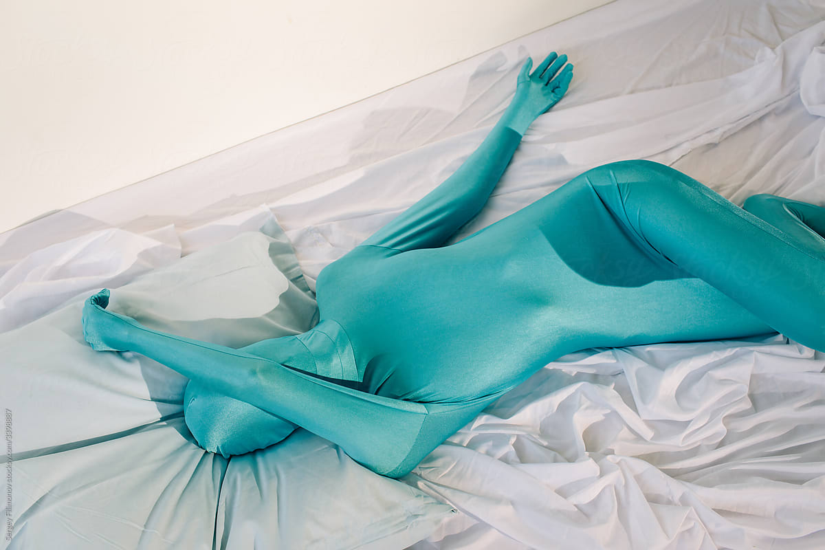 Anonymous person in odd colorful wear lying on bed