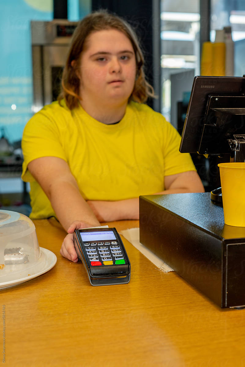 Young woman with Down syndrome works at the cash register
