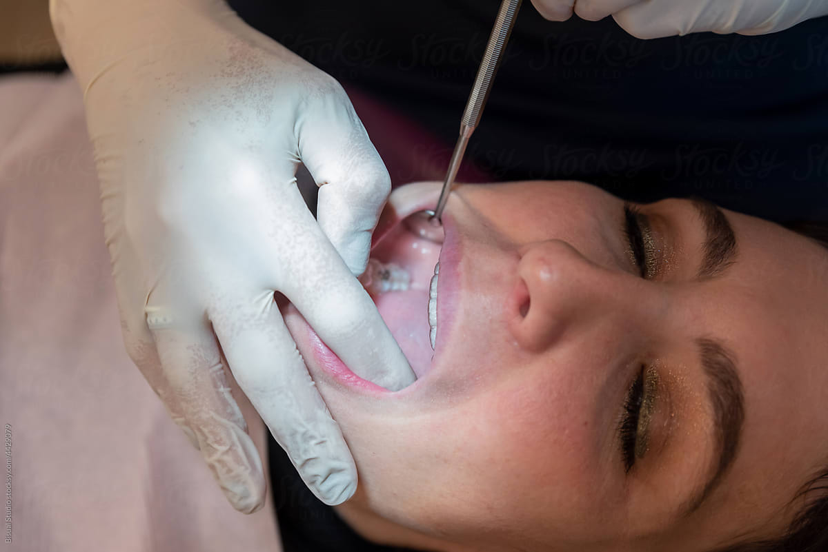 Faceless dentist examining invisible orthodontics of female patient