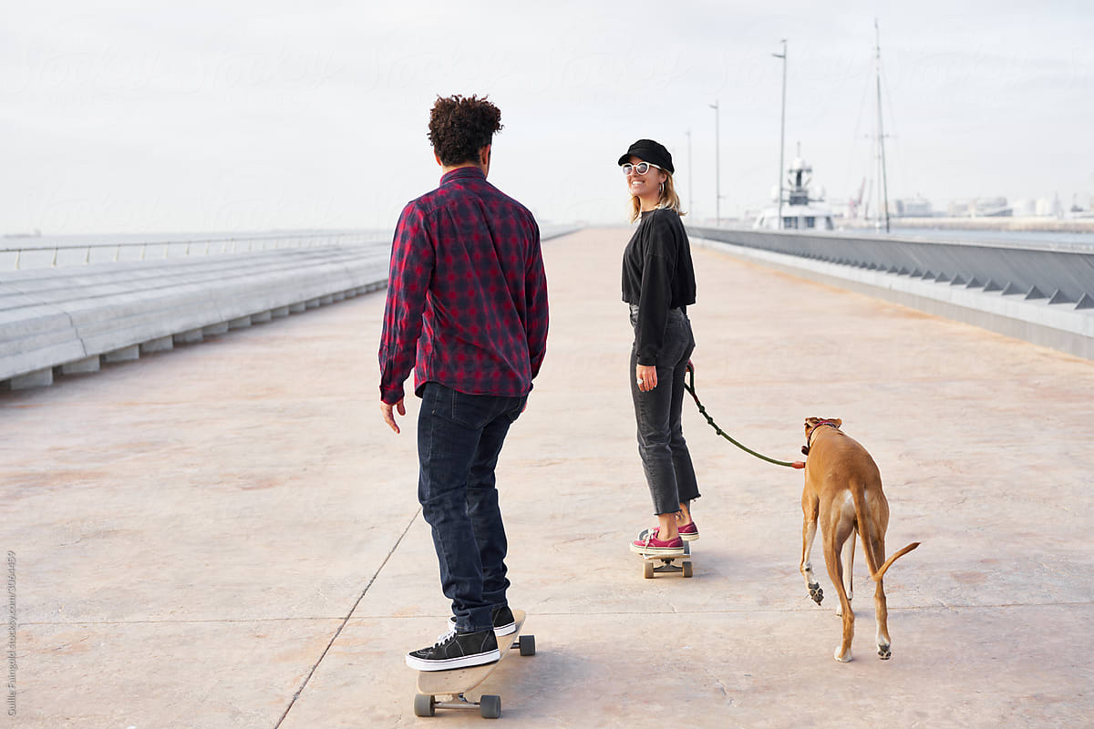 Couple with dog skateboarding on bridge