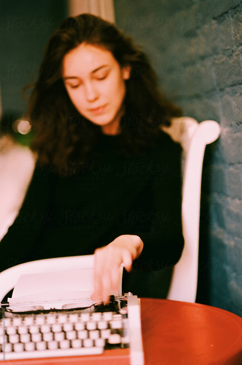Young Woman Typing on Vintage Typewriter Indoors