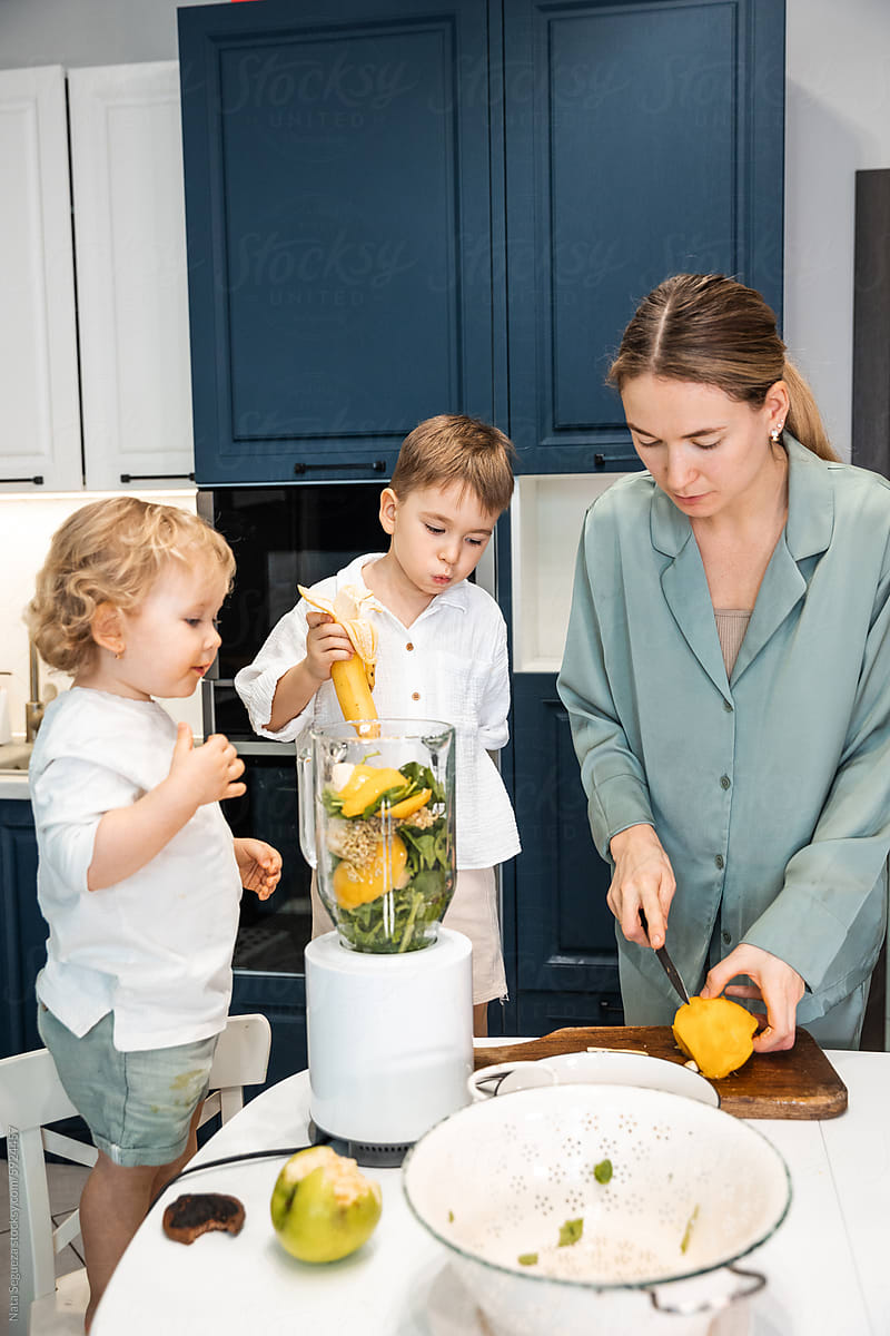 A woman and her kids are making smoothies