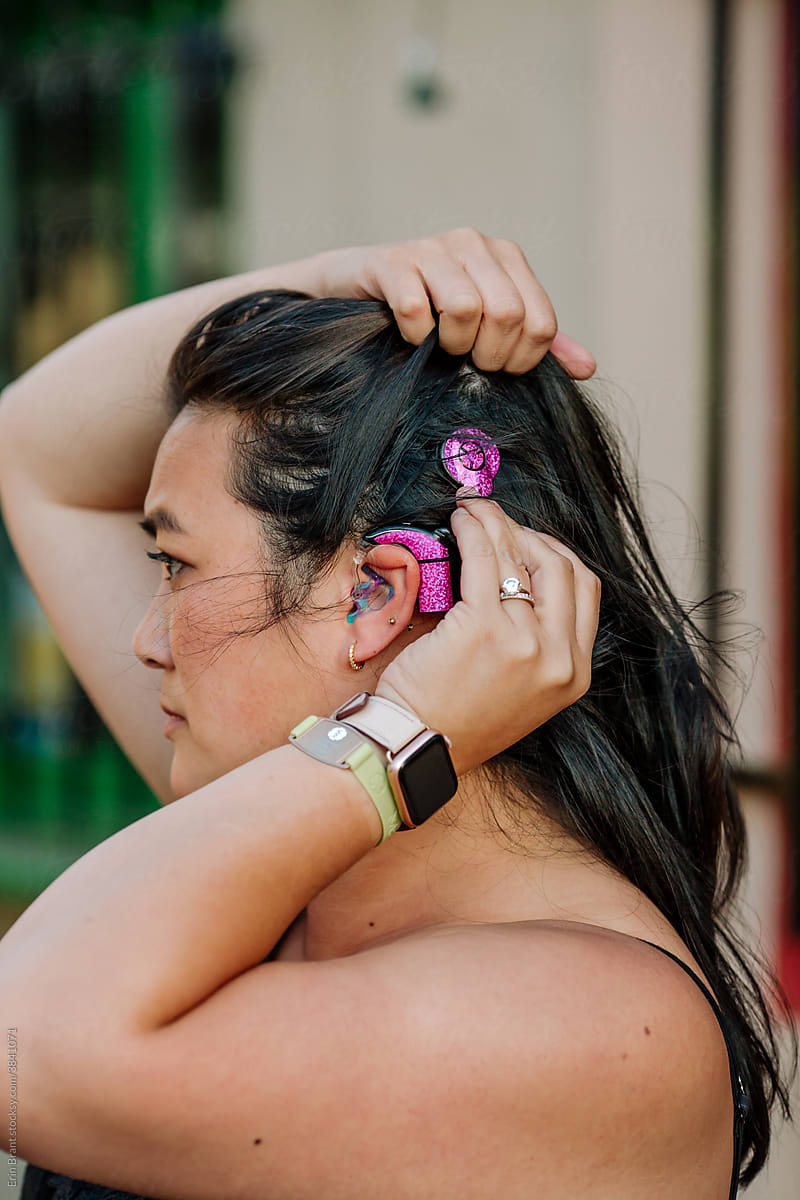 Woman adjusting pink cochlear implant