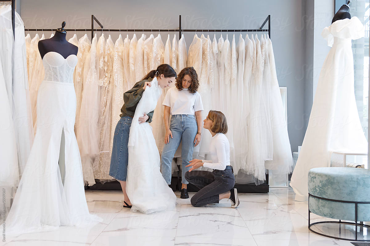 Seller assisting woman buying wedding dress in shop