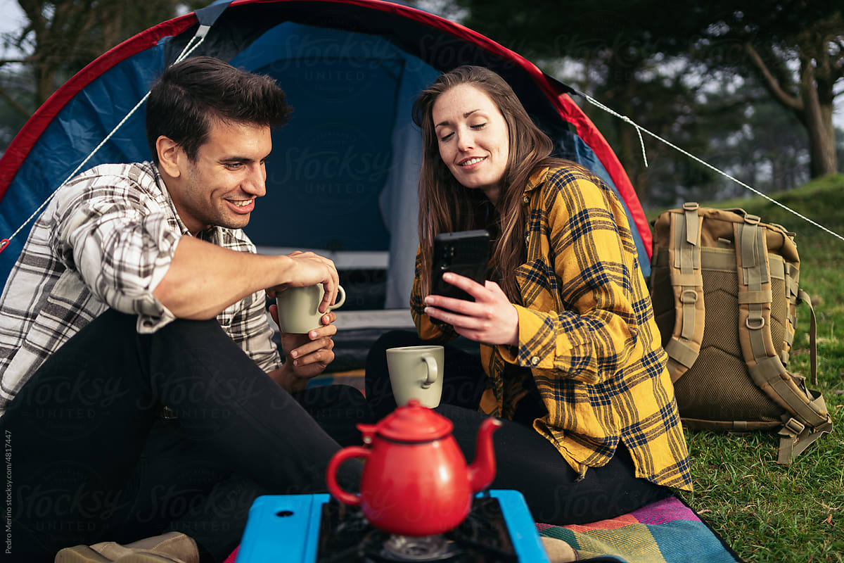 Couple camping in the forest and using smartphone