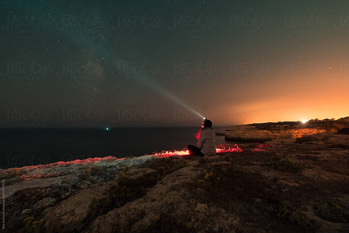 Sitting woman with head flashlight looking at the stars