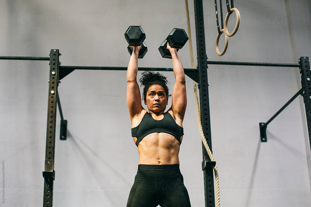 Strong female weightlifter exercising with dumbbells