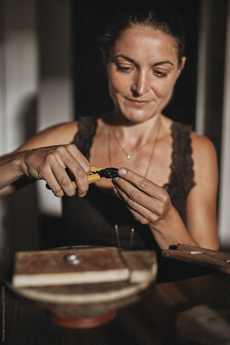 Smiling female jeweler using her pliers to shape a ring