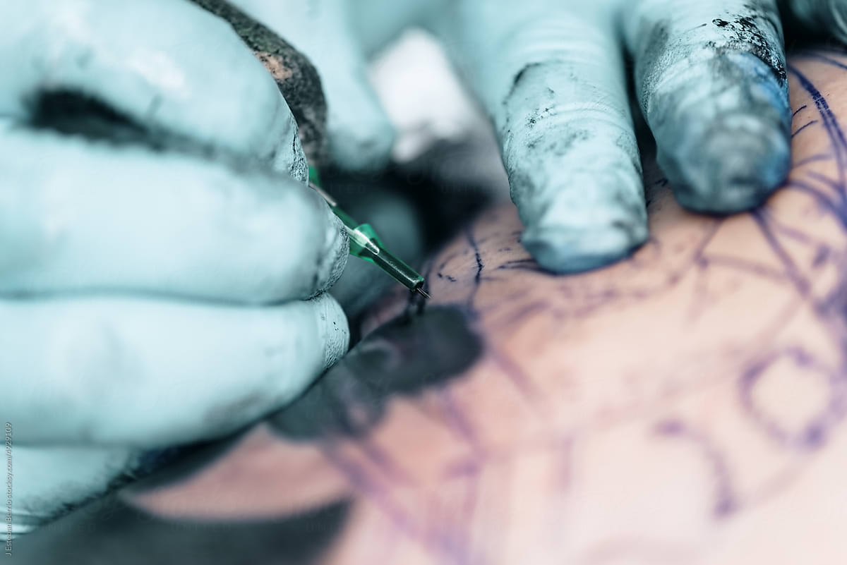 Detail of a three-needle tattoo machine on the skin.