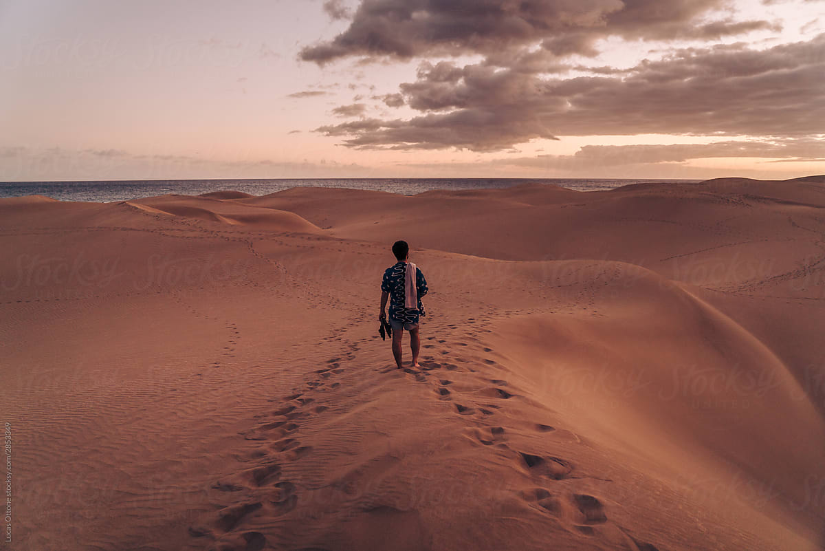 Man walking across sand dunes